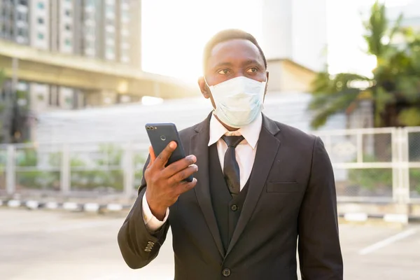 Portrait of African businessman with mask for protection from corona virus outbreak in the city streets outdoors