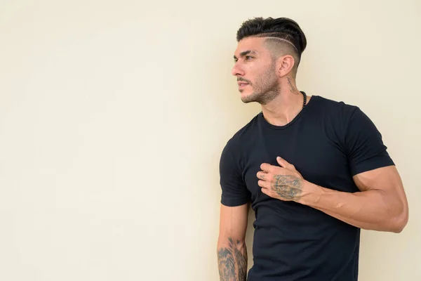 Genç, yakışıklı, sakallı, İranlı adam düşünüyor ve başka tarafa bakıyor.