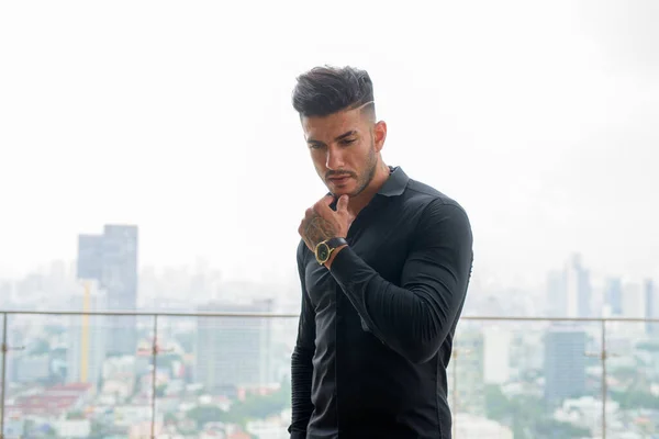 Genç, yakışıklı, sakallı, İranlı iş adamı şehirde düşünüyor.