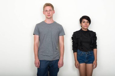 Studio shot of young blond man and young Asian woman as multi ethnic couple together against white background