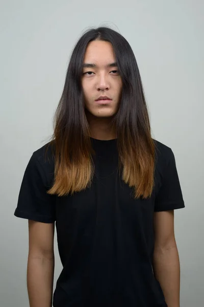 スタジオショットの若いですアジアの男とともに長い髪で灰色の背景 — ストック写真