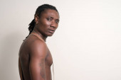 Gestresster junger muskulöser afrikanischer Mann mit Dreadlocks, der hemdlos zurückblickt