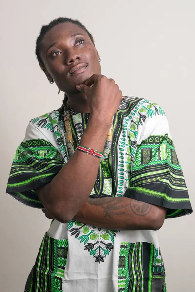 Ung stilig afrikansk man med dreadlocks i traditionella kläder och tänkande — Stockfoto