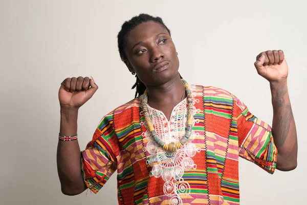 Ung vacker afrikansk man med dreadlocks i traditionella kläder tänkande med knytnävar upp — Stockfoto