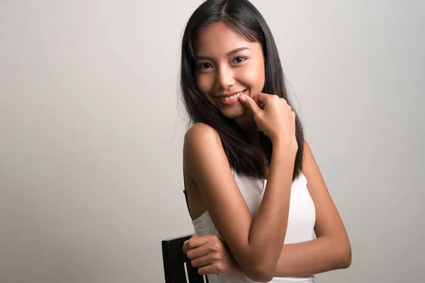Gelukkig jong mooi aziatisch tiener meisje zitten — Stockfoto
