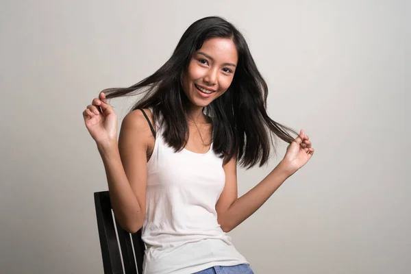 Glücklich junge schöne asiatische Teenager Mädchen sitzen und lächeln — Stockfoto