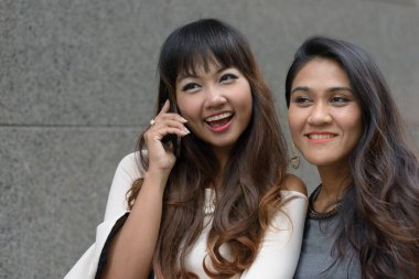 Portrait of two young Asian businesswomen together in the city outdoors