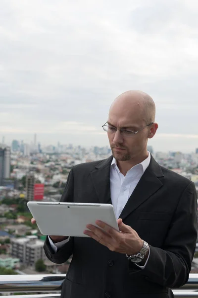 Красивый лысый бизнесмен, использующий цифровой планшет против вида на город — стоковое фото