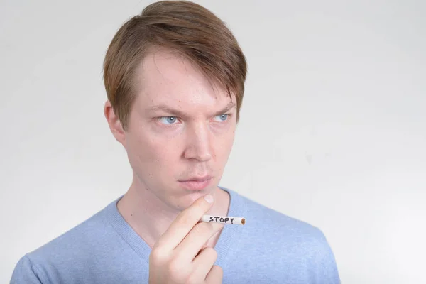Portret młodego mężczyzny wyglądającego poważnie trzymającego papierosa ze znakiem STOP — Zdjęcie stockowe