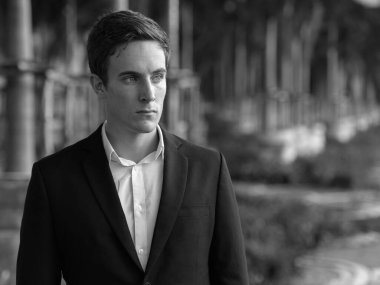 Portrait of young handsome businessman in suit at the airport outdoors in black and white