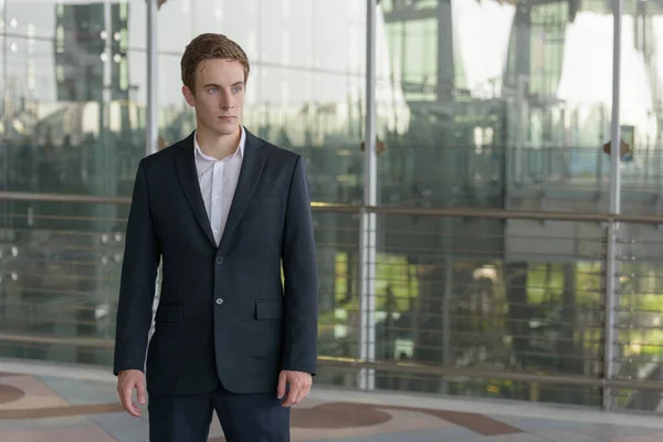 Portrait of young handsome businessman in suit at the airport outdoors