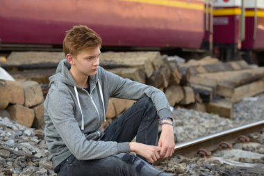 Portrait of young handsome teenage boy at the railway train station