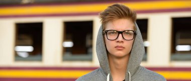 Portrait of young handsome teenage boy at the railway train station