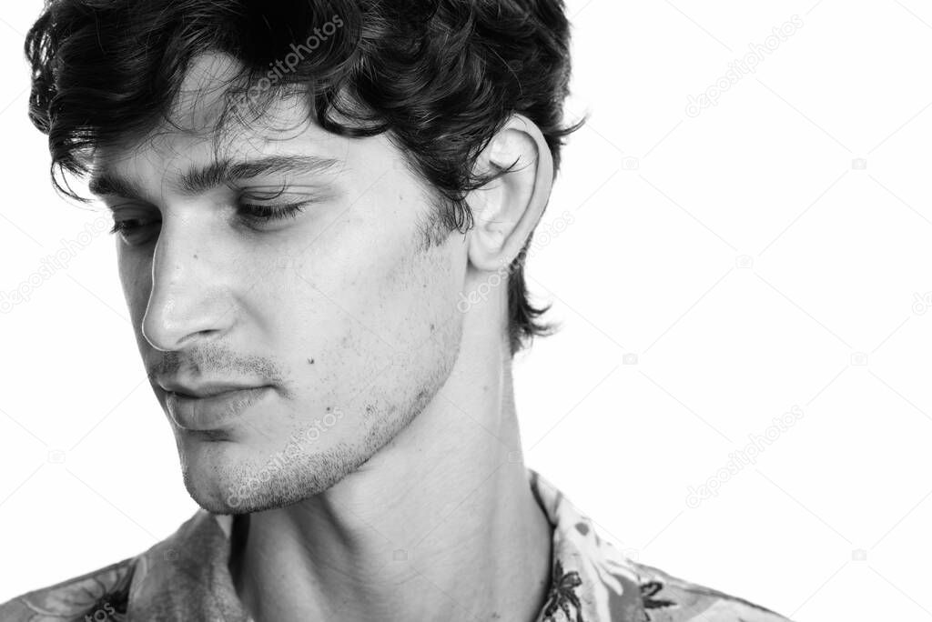 Studio shot of young handsome Brazilian man isolated against white background in black and white