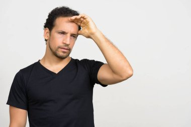 Studio shot of handsome bearded Hispanic man with curly hair against white background