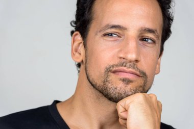 Studio shot of handsome bearded Hispanic man with curly hair against white background