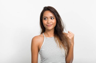 Studio shot of young beautiful Asian woman with brown hair against white background