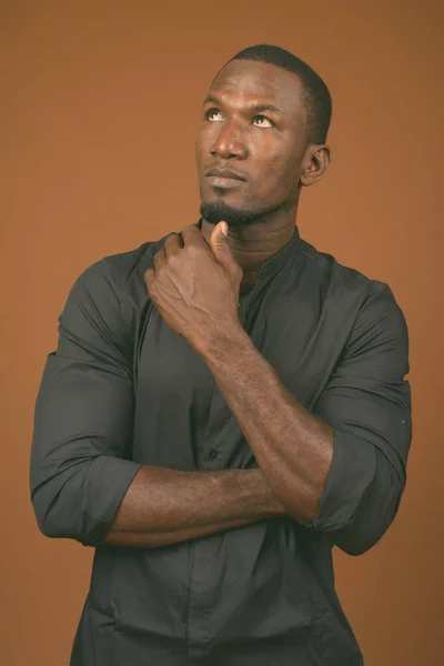 非洲英俊商人穿着褐色背景的黑色衬衫的摄影棚照片 — 图库照片