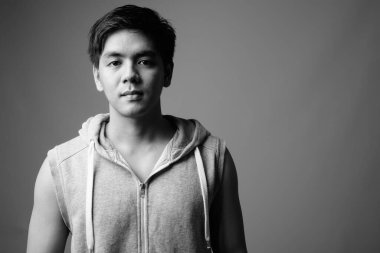 Filipinli genç adamın gri arkaplanlı siyah beyaz fotoğrafına karşı.
