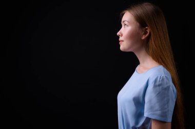 Studio shot of young beautiful woman with long brown hair against black background