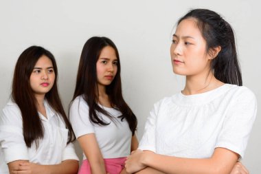 Studio shot of three young beautiful Asian women as friends together against white background