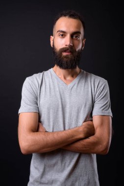 Studio shot of young handsome Persian man with dreadlocks against black background