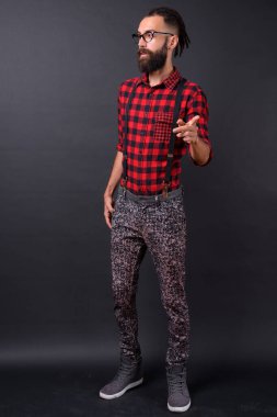 Studio shot of young handsome Persian man with dreadlocks against black background