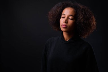 Siyah arka planda Afro saçlı güzel Afrikalı bir kadının stüdyo fotoğrafı.