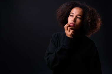 Siyah arka planda Afro saçlı güzel Afrikalı bir kadının stüdyo fotoğrafı.