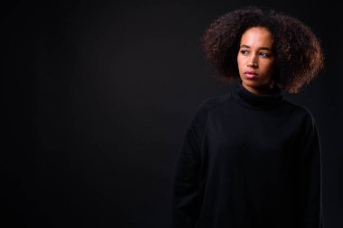 Siyah arka planda Afro saçlı güzel Afrikalı bir kadının stüdyo fotoğrafı.