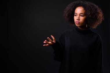 Siyah arka planda Afro saçlı güzel Afrikalı bir kadının stüdyo fotoğrafı.
