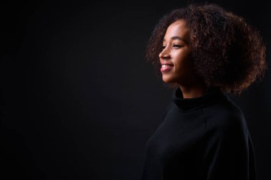 Siyah arka planda Afro saçlı güzel Afrikalı bir kadının stüdyo fotoğrafı.