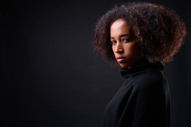 Siyah arka planda Afro saçlı güzel Afrikalı bir kadının stüdyo fotoğrafı.