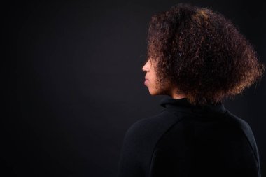 Siyah arka planda Afro saçlı güzel Afrikalı bir kadının stüdyo fotoğrafı.