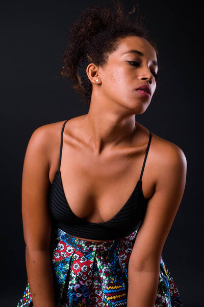 Studio shot of young beautiful African woman with Afro hair against black background