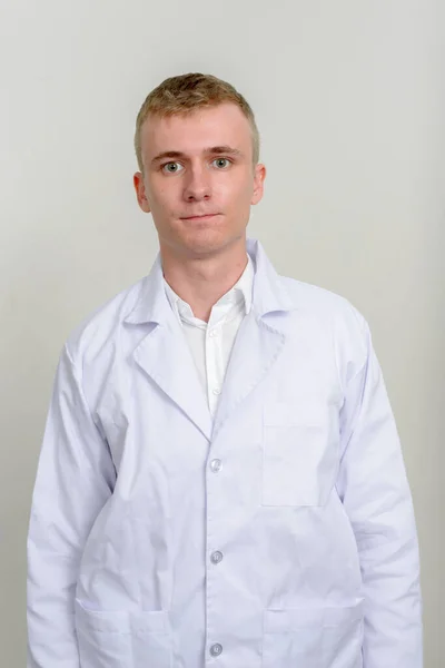 白い背景に対してブロンドの髪を持つ若い男の医者のスタジオショット — ストック写真