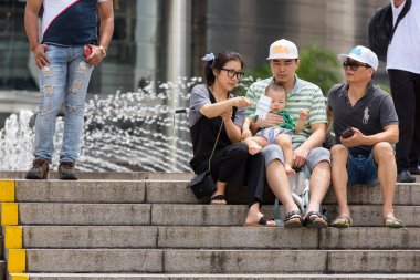 KUALA LUMPUR, MALAYSIA - 20 Şubat 2017 - Asyalı turist ailesi KLCC parkında fıskiyeli cep telefonu ve selfie çubuğuyla fotoğraf çekiyor
