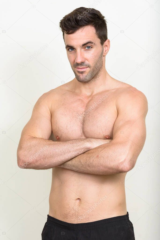 Studio shot of handsome Hispanic man shirtless against white background