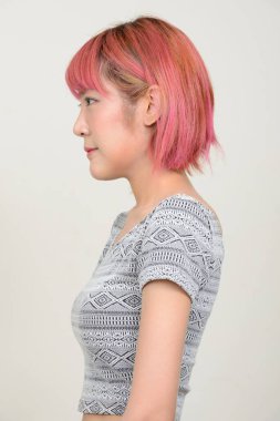 Beyaz arka planda pembe saçlı güzel Asyalı kadının stüdyo fotoğrafı.