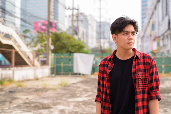 Portrait of young handsome Filipino hipster man in the city streets outdoors