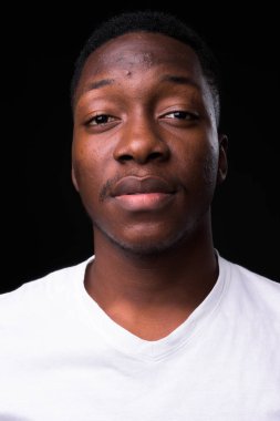 Siyah arka planda Afro saçlı yakışıklı Afrikalı genç adamın stüdyo fotoğrafı.