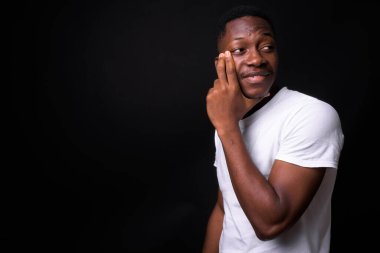 Siyah arka planda Afro saçlı yakışıklı Afrikalı genç adamın stüdyo fotoğrafı.