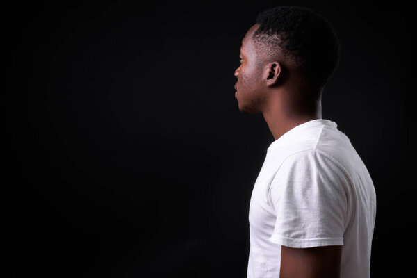 Studio shot of young handsome African man with Afro hair against black background
