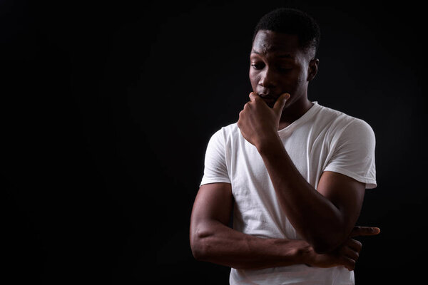 Studio shot of young handsome African man with Afro hair against black background