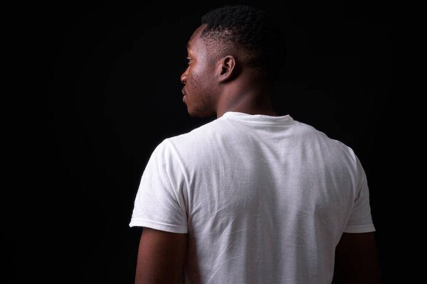 Studio shot of young handsome African man with Afro hair against black background