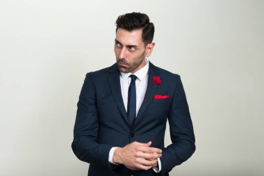 Beyaz arka planda takım elbise giyen yakışıklı sakallı iş adamının stüdyo fotoğrafı.