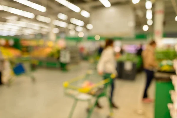Portrait of blurred customers shopping for groceries in supermarket loaded with variety of products on shelves