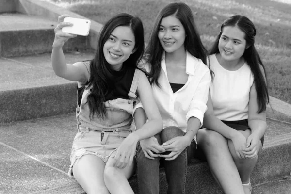 三个年轻的亚洲女人在公园外面穿着黑白相间在一起放松的形象 — 图库照片