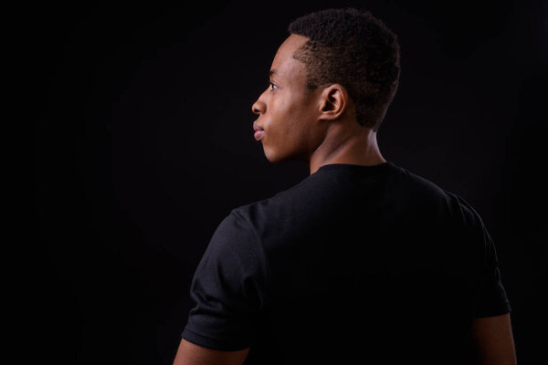 Studio shot of young handsome African man against black background