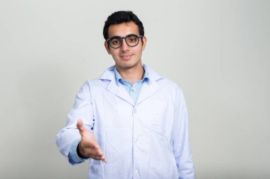 Beyaz arka planda genç ve yakışıklı Hintli doktorun stüdyo fotoğrafı.